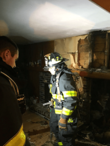 fireman in suit looking through damaged house